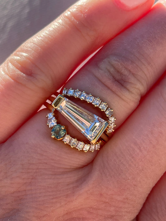 closeup of tapered baguette diamond ring with a top and bottom stacking ring on a women's hand.