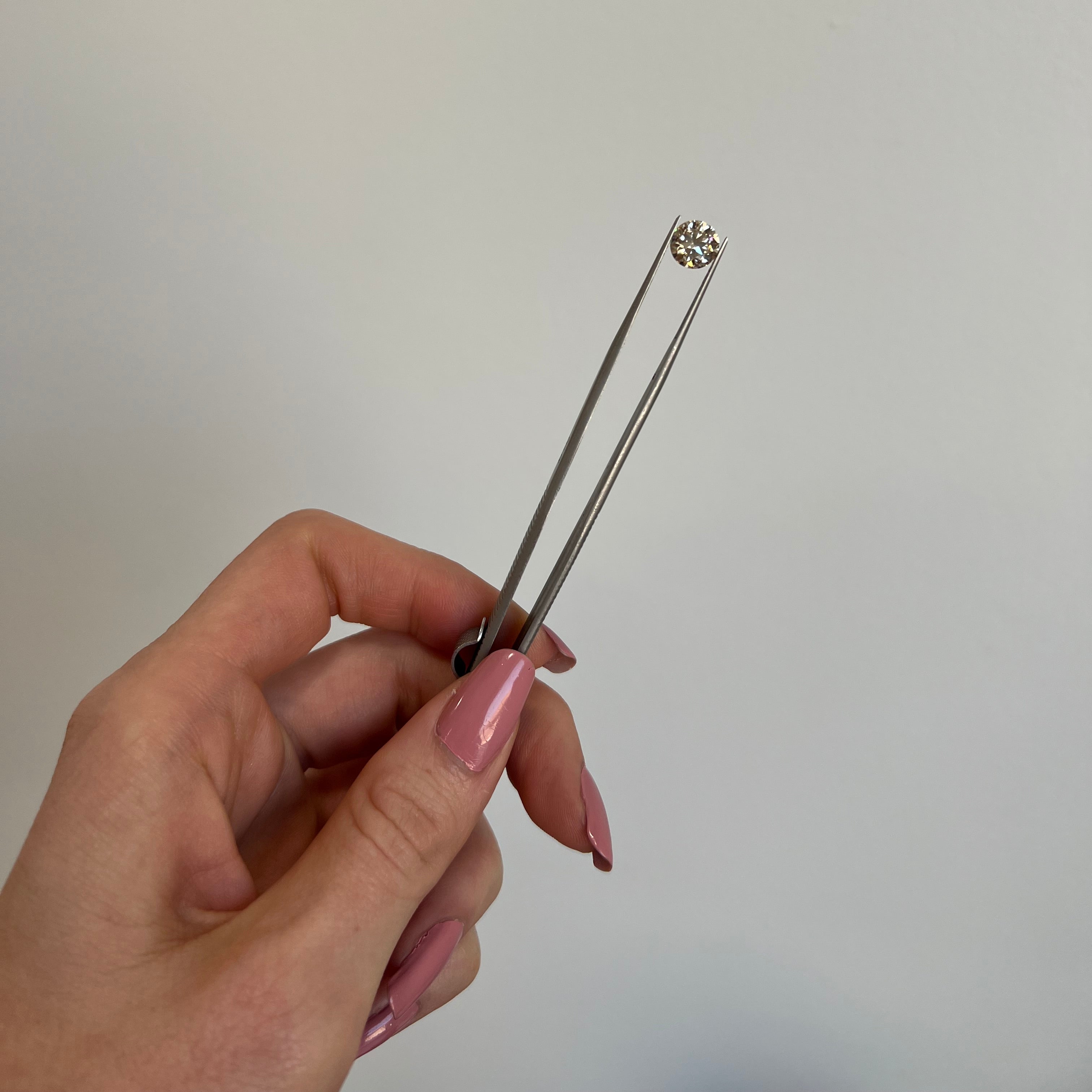 Hand holding a small metal tool against a plain background