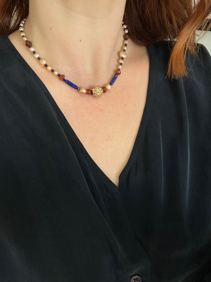 Close-up of a person wearing a beaded necklace with a dark top.