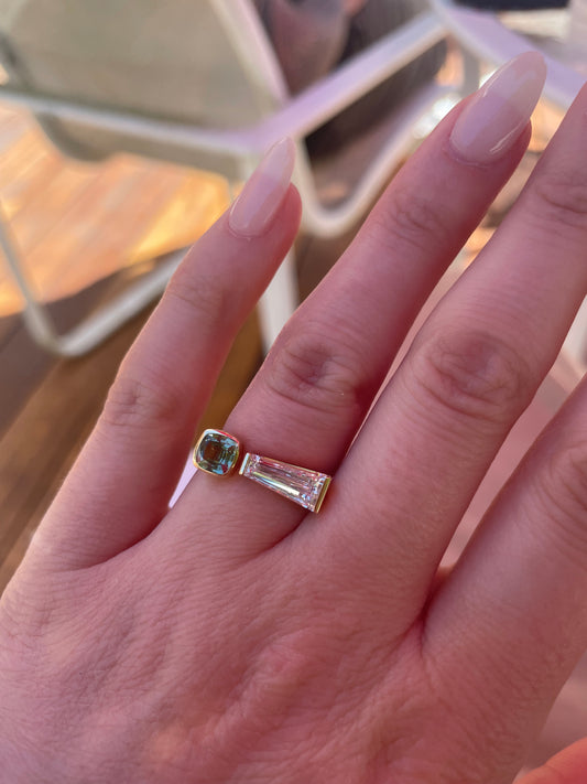 Closeup of tapered baguette diamond and sapphire ring on hand