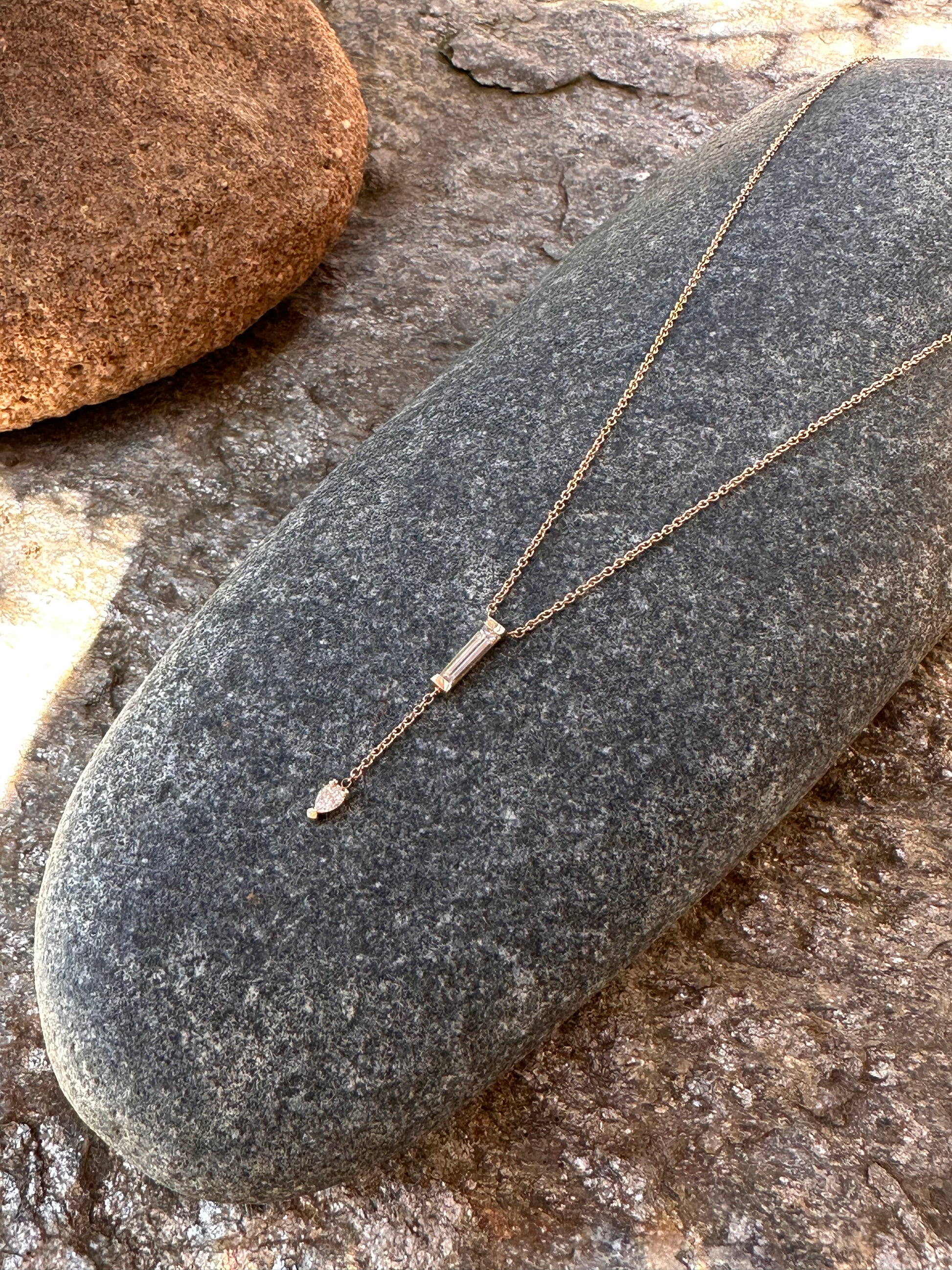 Diamond and yellow gold necklace on a dark stone.