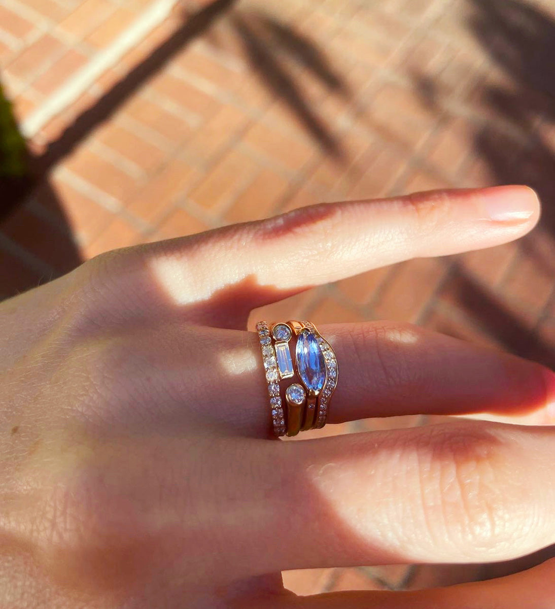 Close up of hand featuring 4 stacking diamond rings.
